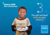 Virtual charity Christmas gift card design featuring smiling young boy holding a plate of food against a blue starry background with text reading 'Feed a child this Christmas' and 'This gift will feed three hungry children.' A Mary's Meals logo appears in the lower right.